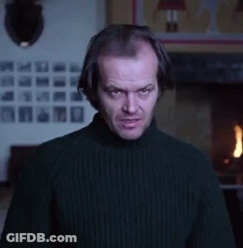 A Man In A Black Sweater Is Standing In Front Of A Fireplace And Making A Funny Face . GIF