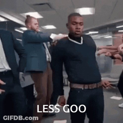 A Man In A Black Sweater Is Standing In Front Of A Group Of People With The Words Less Goo Written On The Bottom . GIF