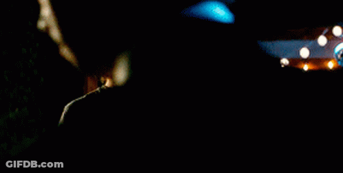 A Man In A Black Sweater Is Talking On A Cell Phone At Night . GIF