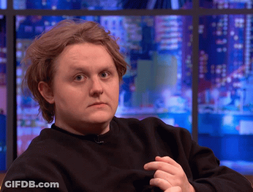 A Man In A Black Sweater Looks At The Camera GIF