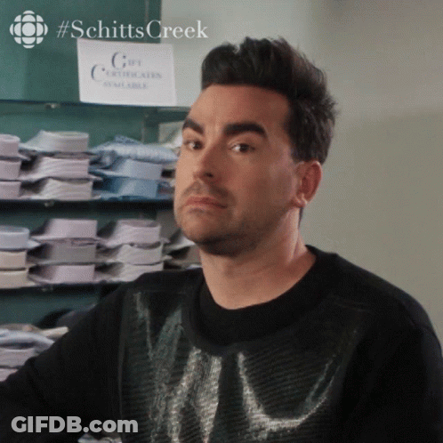 A Man In A Black Sweater Stands In Front Of A Sign That Says Gift Certificates Available GIF