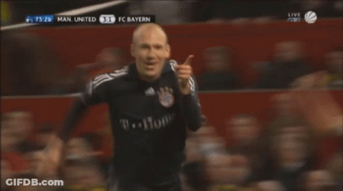 A Man In A Black T-Home Jersey Stands In Front Of A Crowd GIF