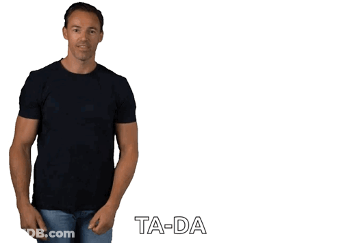 A Man In A Black T-Shirt And Jeans Is Standing In Front Of A White Background With Ta-Da Written On It GIF