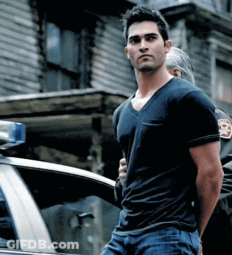 A Man In A Black T-Shirt Is Being Arrested By A Police Officer GIF