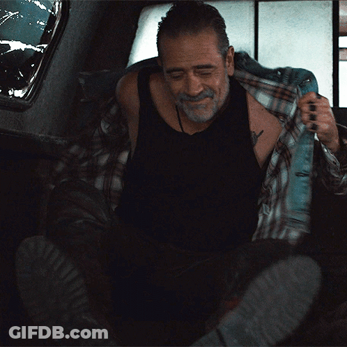 A Man In A Black Tank Top And Plaid Shirt Is Taking Off His Shirt GIF