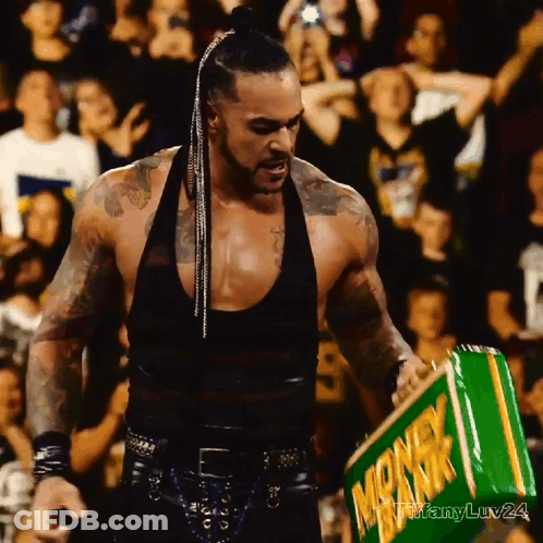 A Man In A Black Tank Top Holds A Green Box That Says Monkeyk GIF