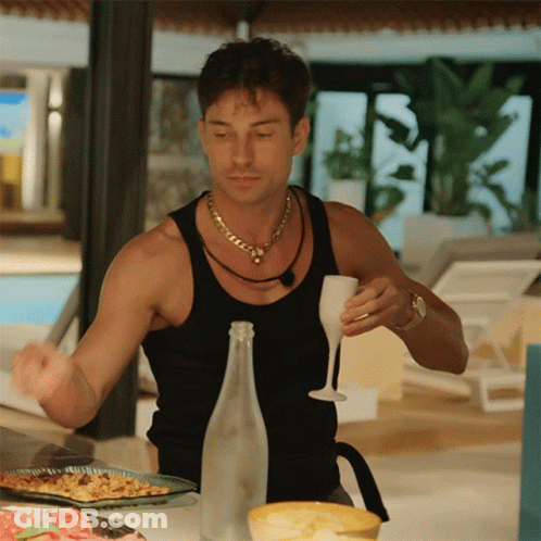 A Man In A Black Tank Top Holds A Wine Glass GIF