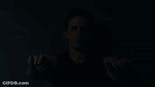A Man In A Black Tank Top Holds His Hands Out GIF