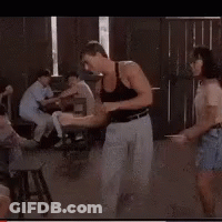 A Man In A Black Tank Top Is Dancing In Front Of A Crowd GIF