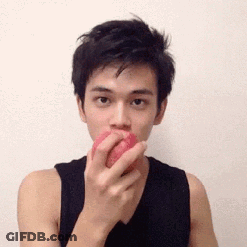 A Man In A Black Tank Top Is Eating A Red Apple . GIF