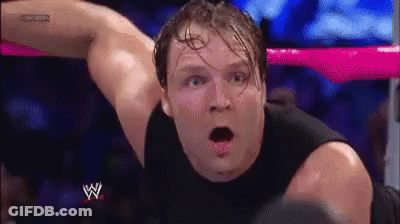 A Man In A Black Tank Top Is Laying In A Wrestling Ring With His Mouth Open And A Surprised Look On His Face . GIF