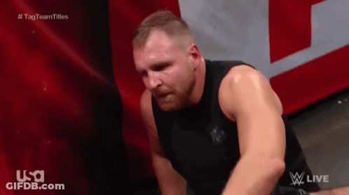 A Man In A Black Tank Top Is Sitting On The Floor With His Head Down . GIF