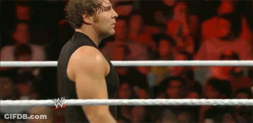 A Man In A Black Tank Top Is Standing In A Wrestling Ring With A Crowd Watching . GIF