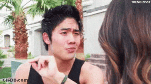 A Man In A Black Tank Top Is Talking To A Woman . GIF