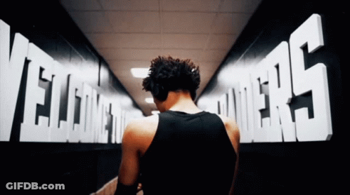 A Man In A Black Tank Top Walks Through A Hallway With The Words Welcome To The Powers On The Wall GIF