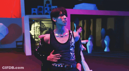 A Man In A Black Tank Top With A Necklace Around His Neck GIF