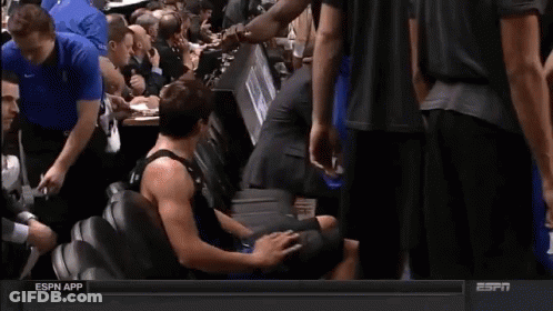 A Man In A Black Tank Top With The Number 1 On It Is Sitting On The Floor GIF