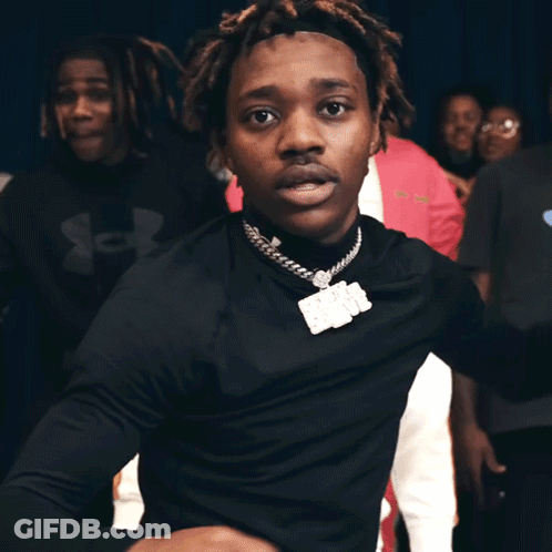 A Man In A Black Turtleneck Is Dancing In Front Of A Crowd Of People GIF