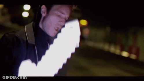 A Man In A Black Turtleneck Is Holding A White Light GIF