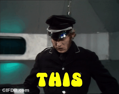 A Man In A Black Uniform Is Standing In Front Of A Yellow Sign That Says This GIF