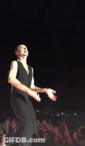 A Man In A Black Vest Is Dancing On A Stage GIF