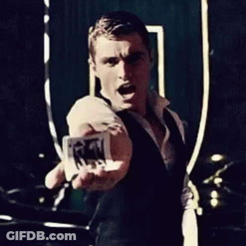 A Man In A Black Vest Is Holding A Piece Of Paper In His Hand GIF