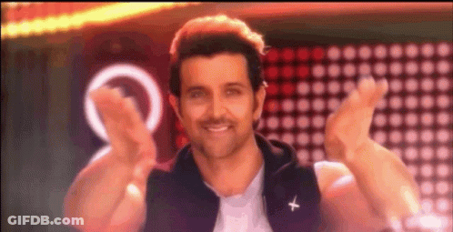 A Man In A Black Vest With A Cross On It Is Smiling And Giving A Peace Sign . GIF