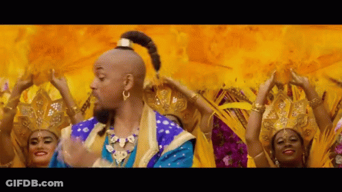 A Man In A Blue And Gold Costume Is Surrounded By Women In Yellow Dresses GIF