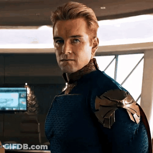 A Man In A Blue And Gold Superhero Costume Is Standing In A Room . GIF