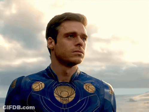 A Man In A Blue And Gold Superhero Costume Looks At The Sky GIF
