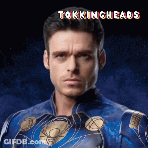 A Man In A Blue And Gold Superhero Costume With The Words Tokingheads Above Him GIF