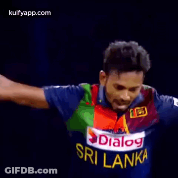 A Man In A Blue And Green Jersey Is Standing In Front Of A Referee . GIF