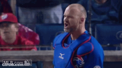 A Man In A Blue And Red Baseball Uniform Is Standing In Front Of A Mlb.com Logo GIF