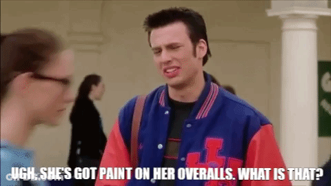 A Man In A Blue And Red Varsity Jacket Is Talking To A Woman In A Hallway . GIF