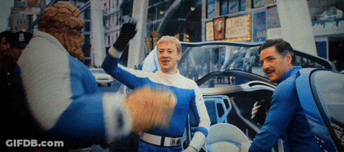 A Man In A Blue And White Costume Stands In Front Of A Sign That Says King Chester On It GIF