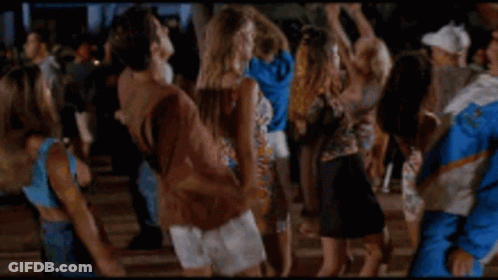 A Man In A Blue And White Jacket Is Dancing In A Crowd Of People . GIF