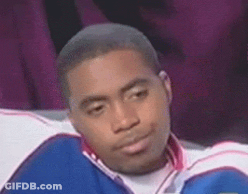 A Man In A Blue And White Jacket Is Sitting On A Couch Making A Funny Face . GIF