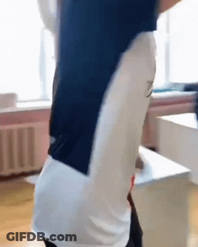 A Man In A Blue And White Shirt Is Standing In A Room With His Arms Outstretched . GIF