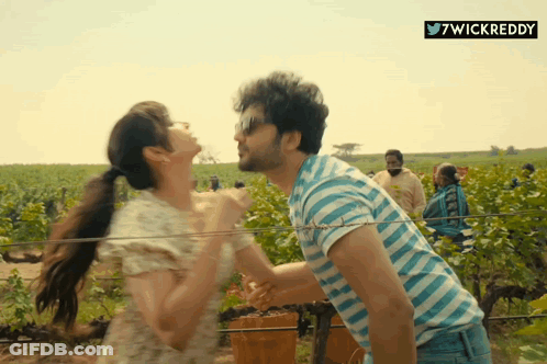 A Man In A Blue And White Striped Shirt Is Carrying A Woman On His Shoulders GIF