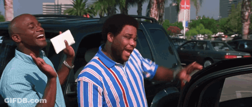 A Man In A Blue And White Striped Shirt Is Laughing With Another Man In A Car GIF
