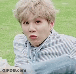 A Man In A Blue And White Striped Shirt Is Sitting In The Grass With A Dog . GIF