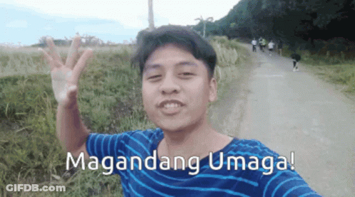 A Man In A Blue And White Striped Shirt Is Waving In Front Of A Sign That Says Maganda GIF