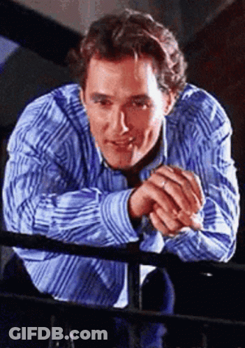 A Man In A Blue And White Striped Shirt Leans On A Railing GIF