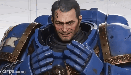 A Man In A Blue Armor Is Smiling And Looking At The Camera With A Screen Behind Him That Says Gamemax GIF