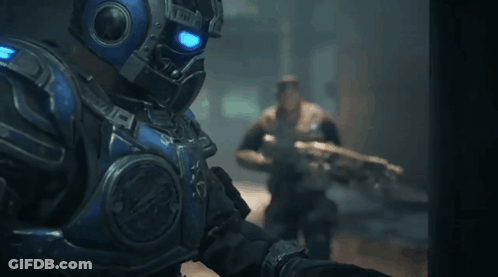 A Man In A Blue Armored Suit Is Holding A Gun GIF