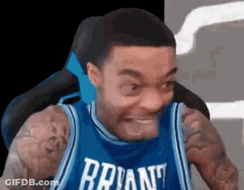 A Man In A Blue Basketball Jersey Is Making A Funny Face . GIF