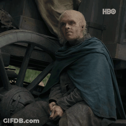 A Man In A Blue Cape Sits In Front Of A Wagon Wheel With The Hbo Logo On The Bottom GIF