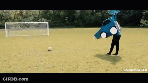 A Man In A Blue Car Costume Is Kicking A Soccer Ball . GIF