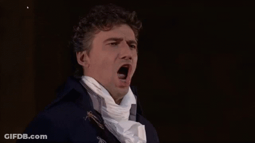 A Man In A Blue Coat And White Scarf Is Yawning . GIF