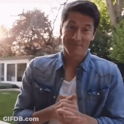 A Man In A Blue Denim Jacket Is Clapping His Hands . GIF